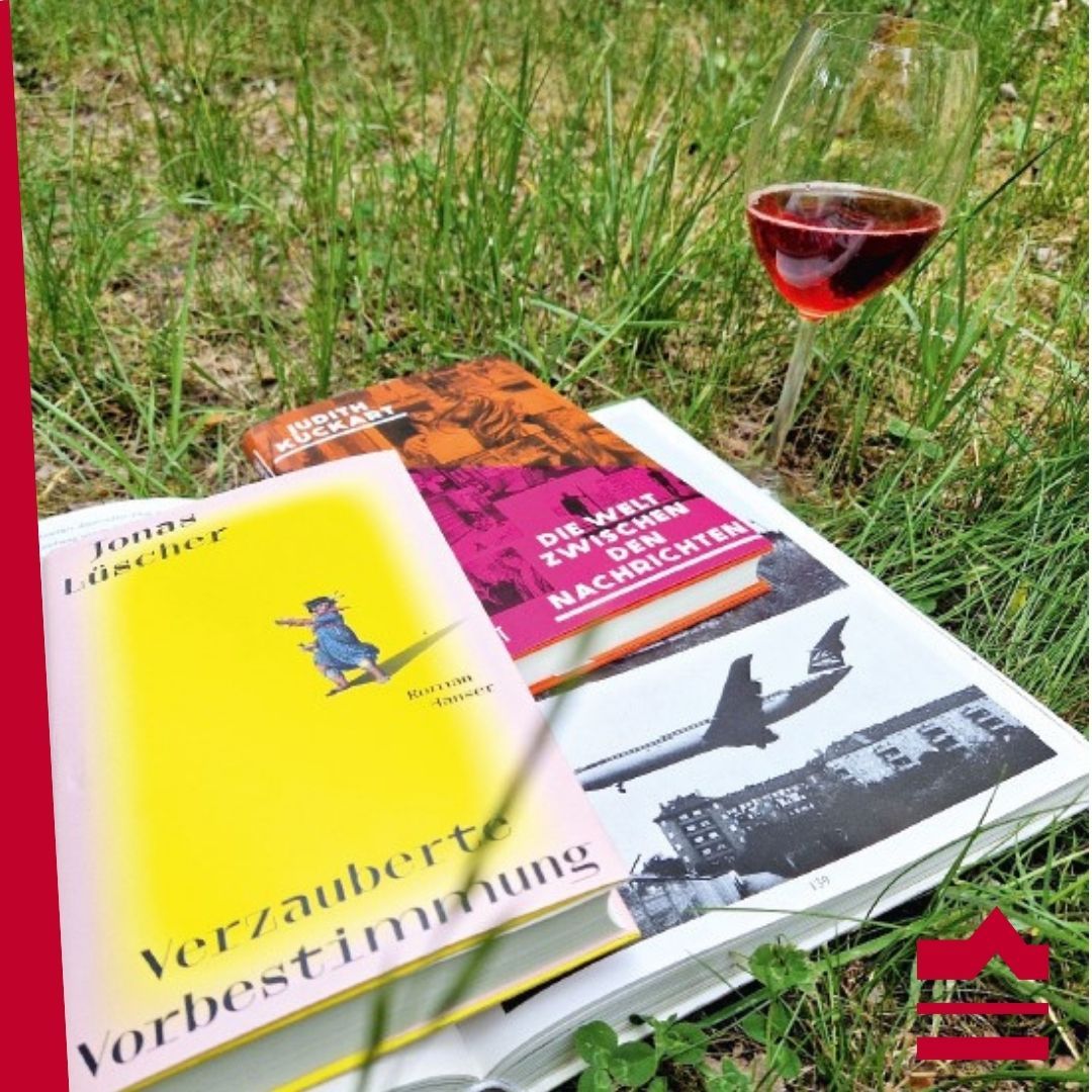 Bücher und ein Glas mit Rotwein im Gras